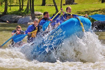 a blue raft gets air off of a big whitewater rapid