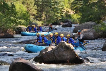 Two blue rafts navigate a rocky river
