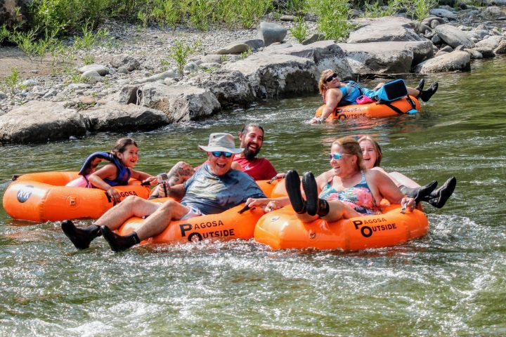 a group of people on tubes laughing while they float a river